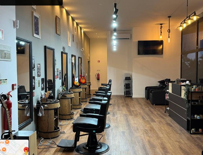 Interior da barbearia com cadeiras, iluminação industrial e guitarras na parede